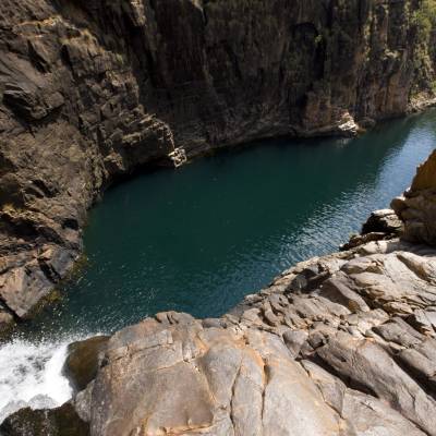 a rocky river with trees on the side of a mountain