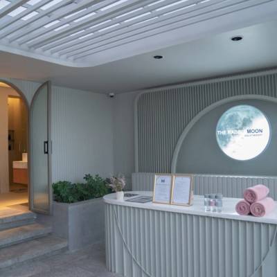 The Rabbit Moon Aquatherapy reception desk with rolled pink towels, moon logo, arched doorway, and green plants at The Salil Hotel Bangkok.