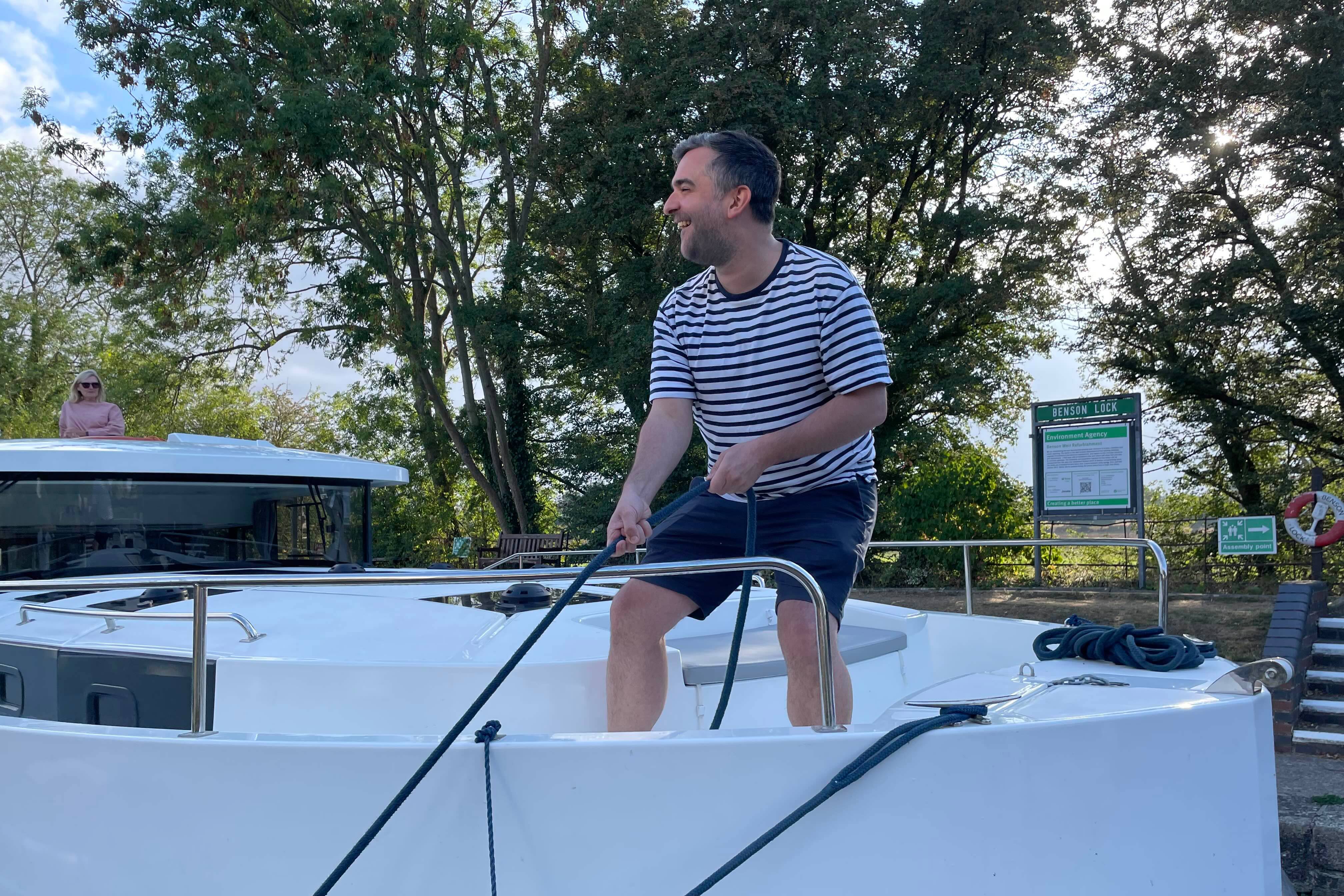 Man handling a rope on the Horizon boat’s deck while preparing to moor at a lock.