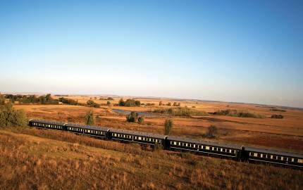 a large long train on a track near a field