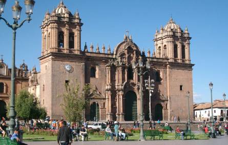 a group of people walking in front of a church with Cusco Cathedral in the background