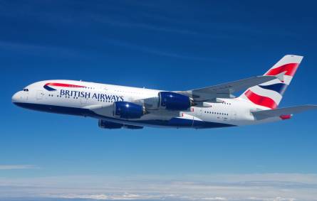 A large British Airways passenger jet flying through a blue sky