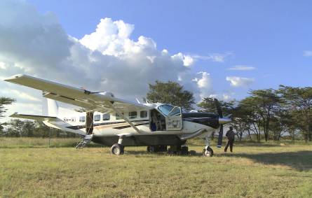 a plane sitting on top of a grass covered field with Castle Air Museum in the background