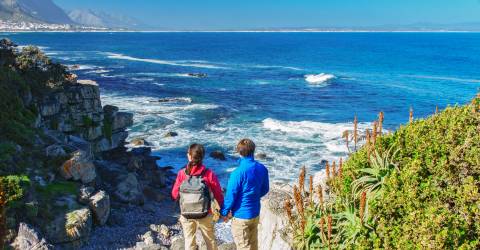 Par som tittar på vyn över havet och Hermanus från utsiktsplats, Sydafrika