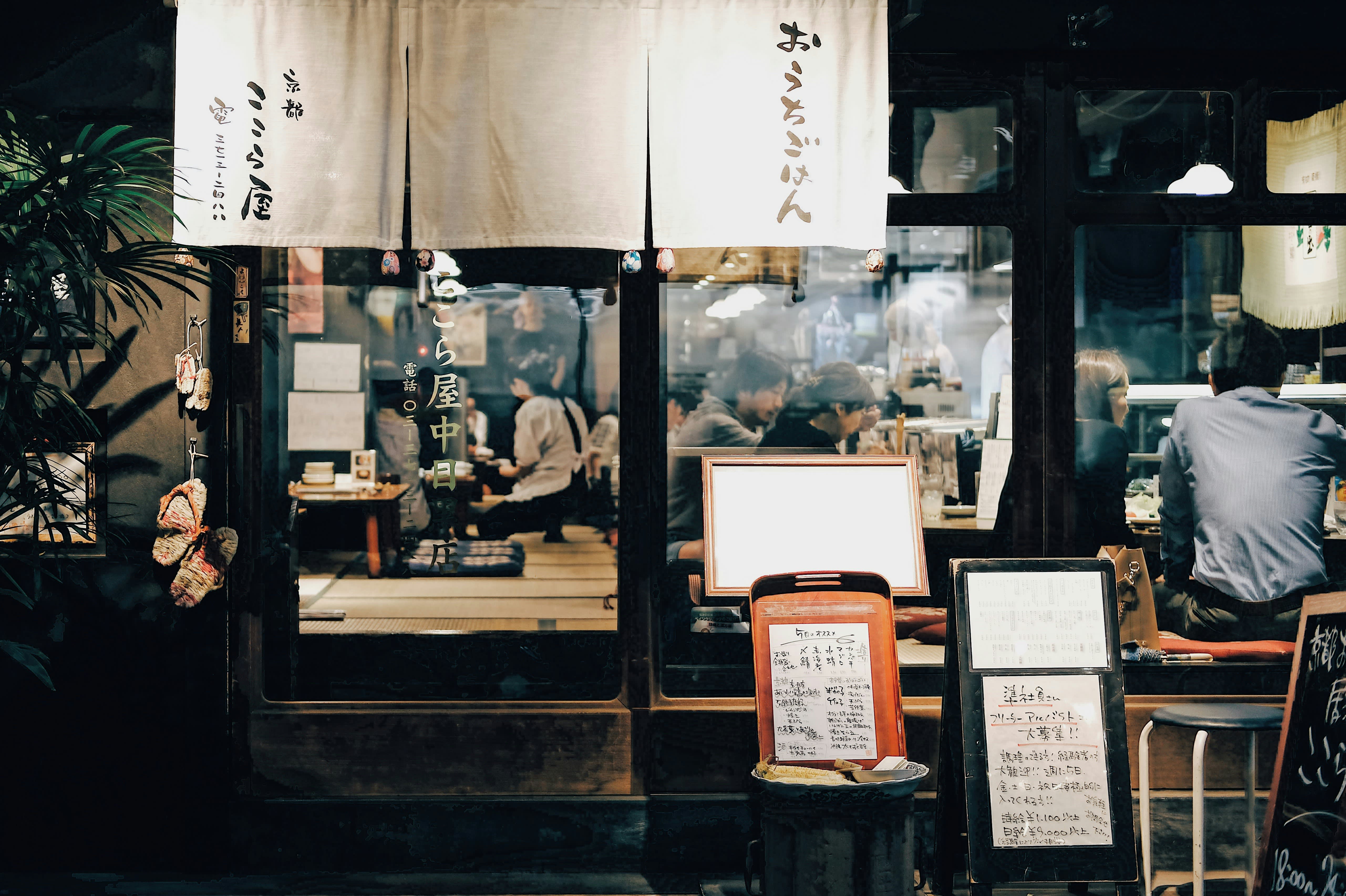 Blick von draußen durch die Glasfenster eines gut besuchten, typisch japanischen Restaurants.
