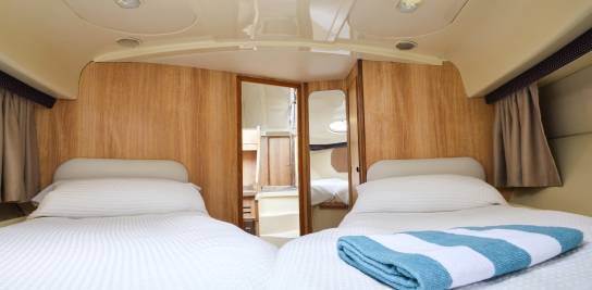 Twin cabin aboard the Consul with two single beds, cosy white bedding, and wood-panelled walls creating a warm, nautical feel.