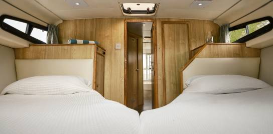 Spacious twin cabin aboard the Caprice with two single beds, overhead hatch, and warm wood panelling throughout.