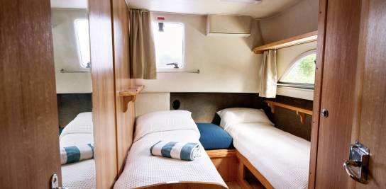 Twin cabin aboard the Classique Star with neatly made single beds, soft white linens, and light filtering through two porthole windows.