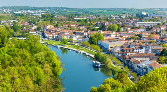 Vue aérienne d’Angoulême avec des bateaux sur la Charente et des berges arborées longeant le quai.