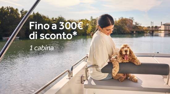 Donna seduta con il suo cane su una barca, mentre naviga tra paesaggi fluviali tranquilli.