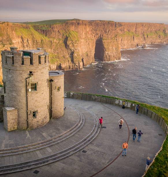 Cliffs of Moher at the west coast of Ireland with a little castle during sunset people tourists