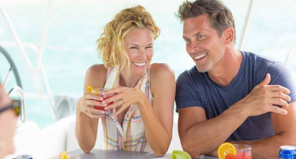Happy couple drinking cocktails on a luxury crewed yacht