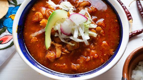 Pozole - A traditional pork or meat stew cooked with spices and garnished with lettuce, peppers, onions, avocado, and salsa