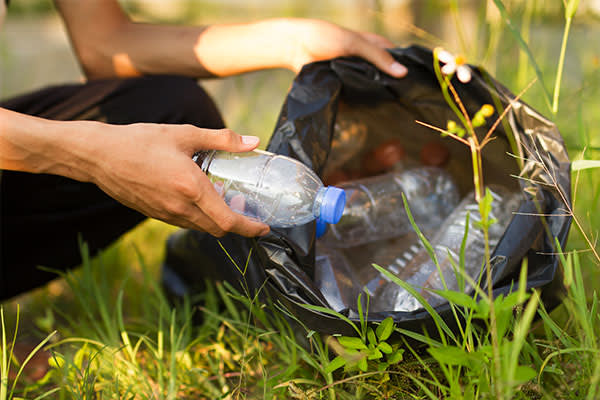 Person picking up trash in nature. 