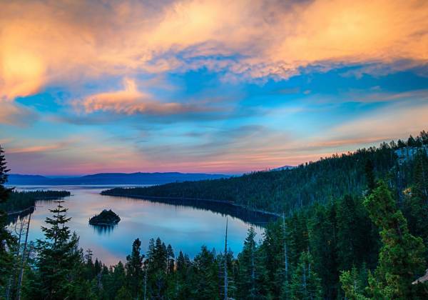 Lake Tahoe water body surrounded by green covers and a clear blue sky