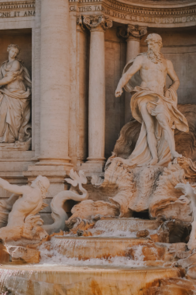Trevi Fountain in Rome featuring Neptune's central marble statue flanked by horses and tritons, with cascading water below.