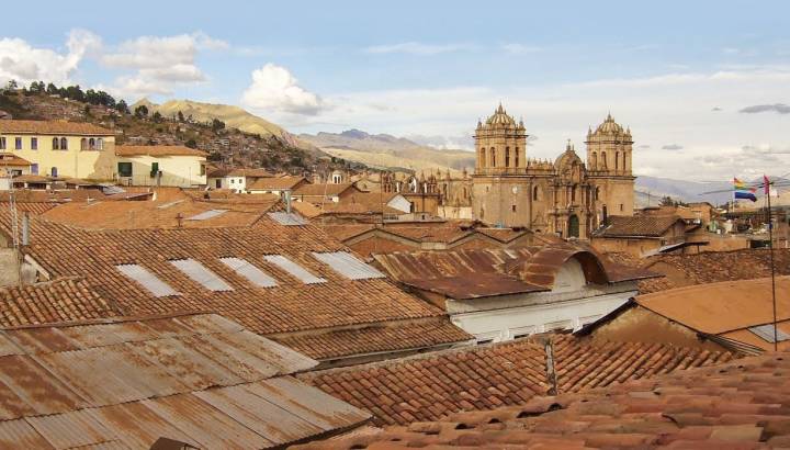 Twin towers and dome of the historic Iglesia de la Compania seen across the red rooftops of Cusco in Peru, South America