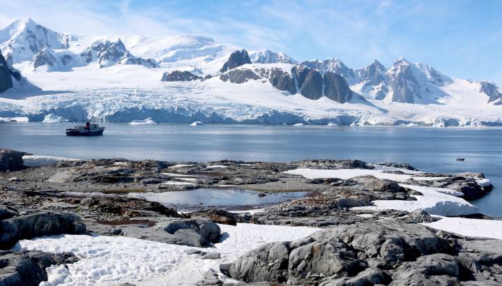 Antarctica water and snow-covered mountains with ship in background