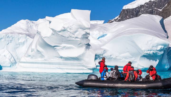 Enchanting Travels Antarctica Tours Boat full of tourists explore huge icebergs