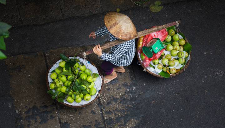 Man carries two baskets with fruits in the yoke, Vietnam, Asia