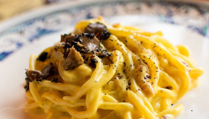Pasta spaghetti with black truffle and olive oil on a white plate.