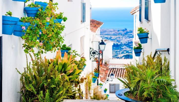 Enchanting Travels Spain Tours Picturesque street of Mijas with flower pots in facades. Andalusian white village. Costa del Sol. Southern Spain