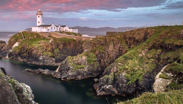 Enchanting Travels UK & Ireland Tours Donegal, Ireland. Fanad head at Donegal, Ireland with lighthouse at sunset. Colorful sky, mountains and sea