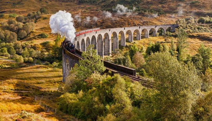 Glenfinnan Viaduct and the Jacobite steam train blowing steam from the exhaust as it crosses the Glenfinnan Viaduct, Highland, Scotland, UK