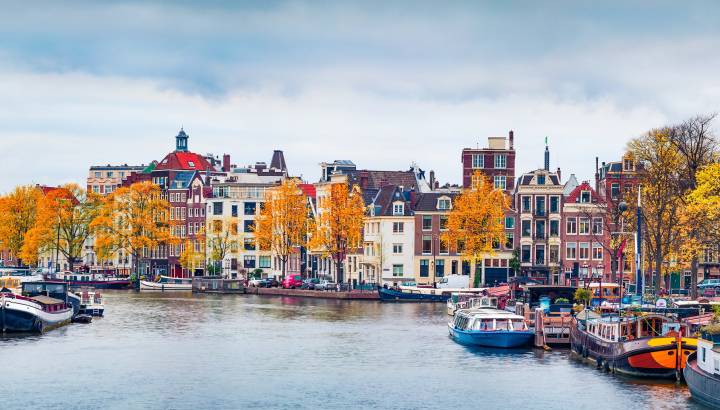 Panoramic autumn view of Amsterdam city. Famous Dutch channels and great cityscape. Gloomy morning scene of Netherlands, Europe. Traveling concept background. European Cities tours