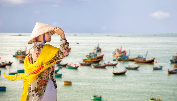 Vietnamese lady with Ao Dai Vietnam traditional dress and conical hat wait at the harbor, Fishing Harbour Mui Ne Vietnam