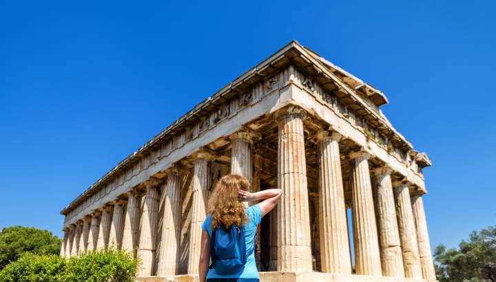 Greece Private Trip:Young woman looks at Temple of Hephaestus, Athens, Greece. This ancient Greek structure is one of main landmarks of Athens.