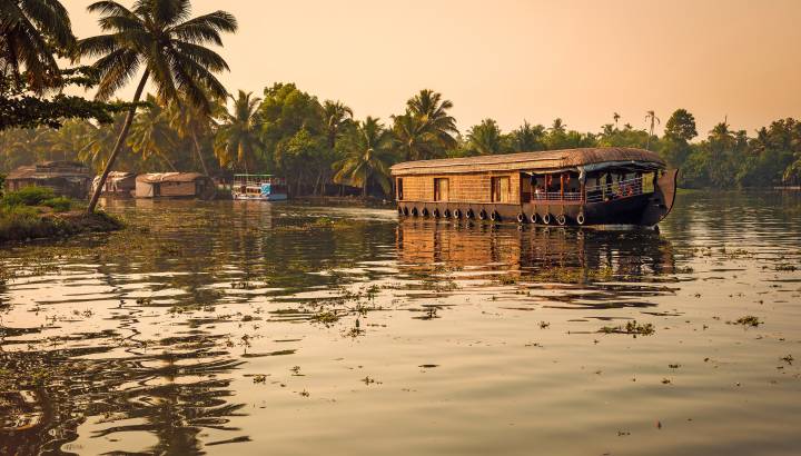Goldene Abendstimmung mit Blick auf ein Hausboot in den Backwaters von Kerala