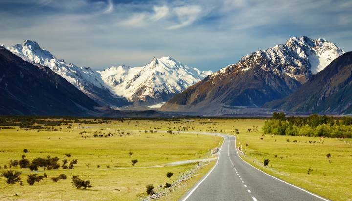 road towards mountains with snow caps in Southern Alps New Zealand