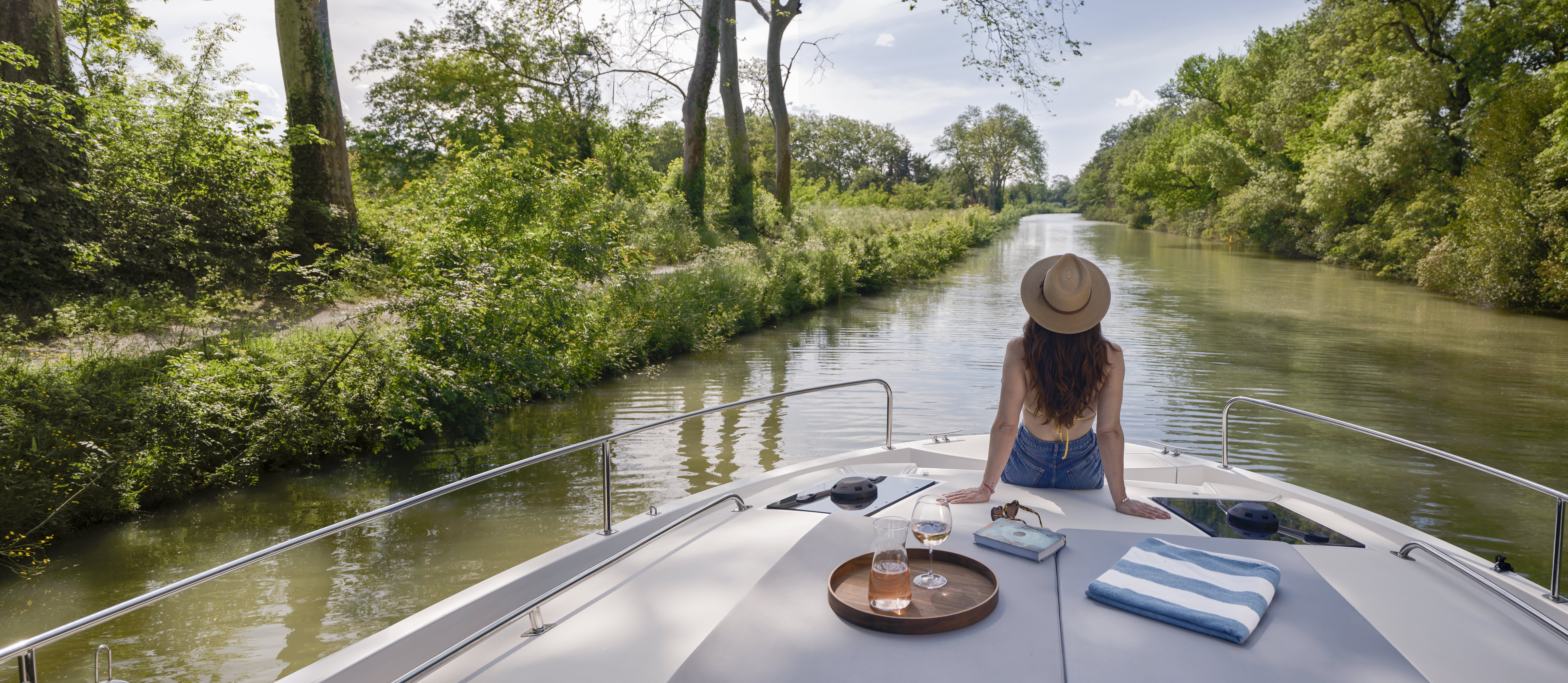 Serene solo moment at the bow of the boat as a woman admires the tree-lined river ahead.
