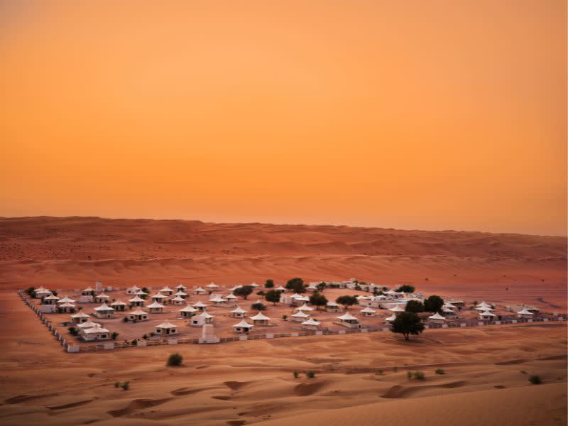 Luftaufnahme bei Sonnenuntergang des Desert Nights Resort Camps in der Wüste Wahiba Sands im Oman