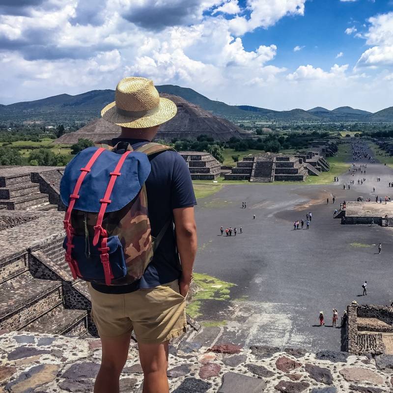 A Mexican American tourist with a backpack and hat