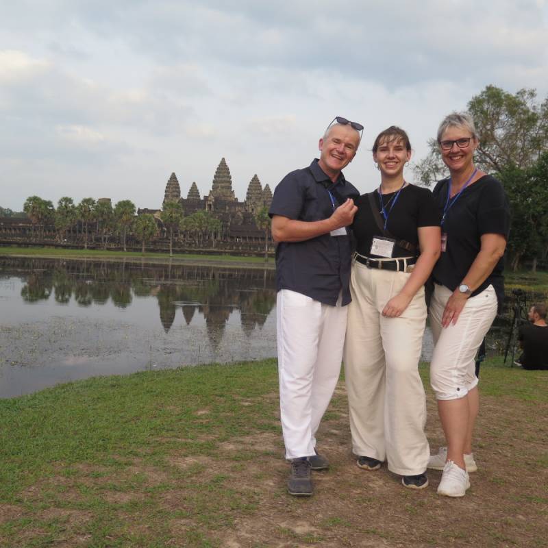 three people standing in front of a waterbody in Cambodia