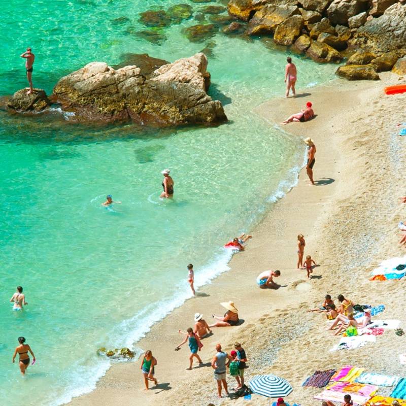 Enchanting Travels France Tours beach of the Cote d'Azur with tourists with sunbeds and umbrellas on the hot summer day