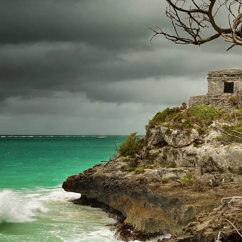 Enchanting Travels Mexico Tours Panoramic view of the old Watchtower in the ancient city of Tulum on the Caribbean coast before it rains, Mexico