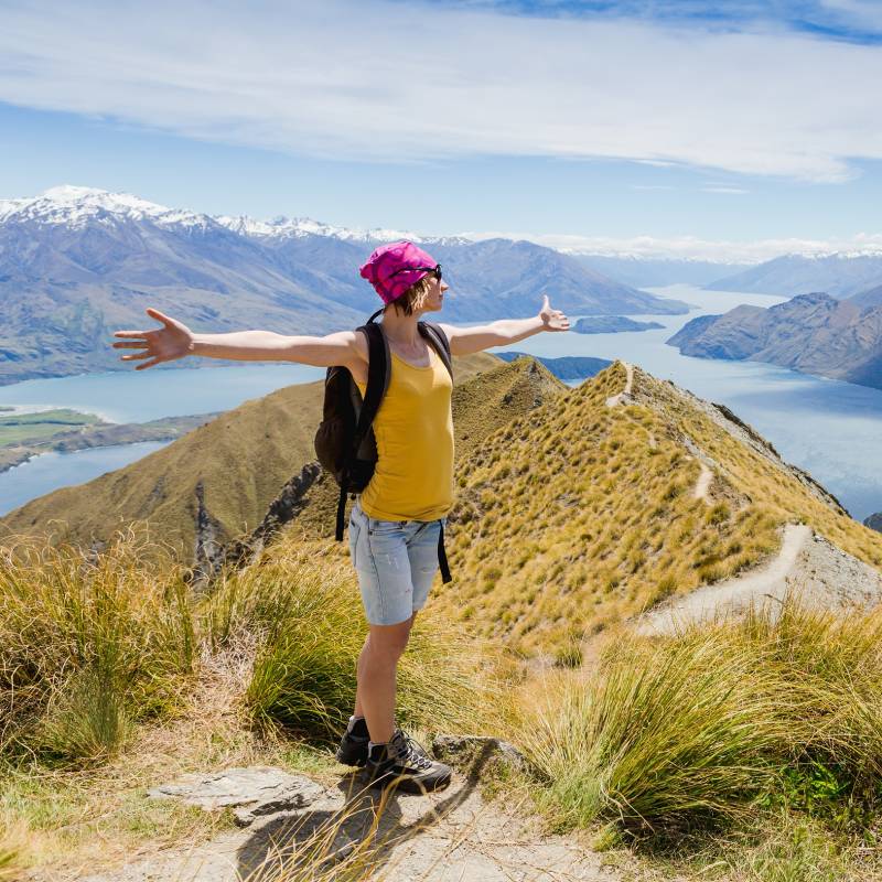 Enchanting Travels New Zealand Tours Woman Traveler with Backpack hiking in Mountains.