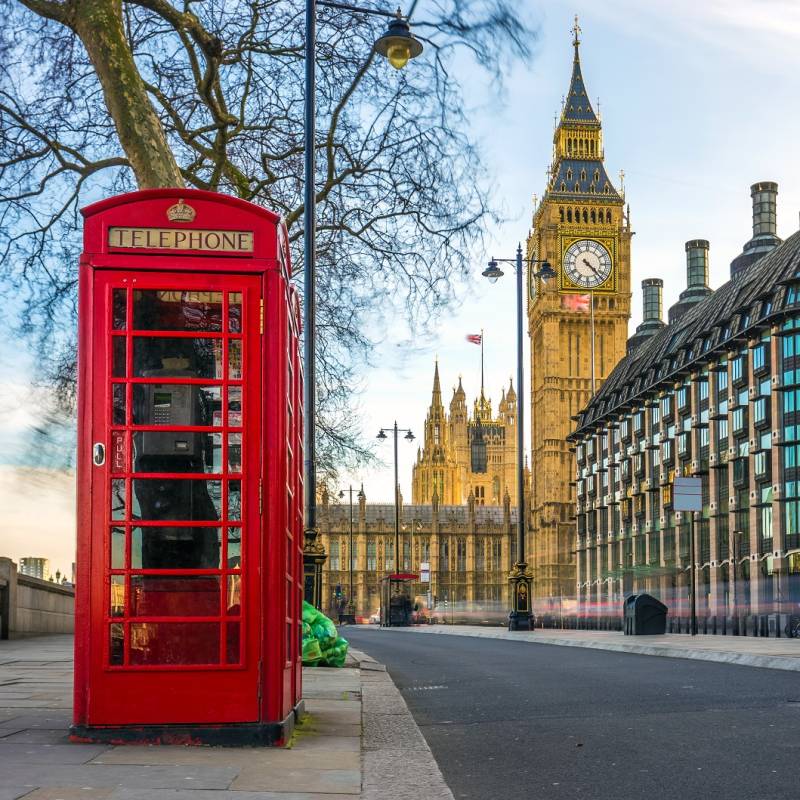 The iconic british old red telephone box with the Big Ben at background in the center of London - Summer is the best time to visit Europe