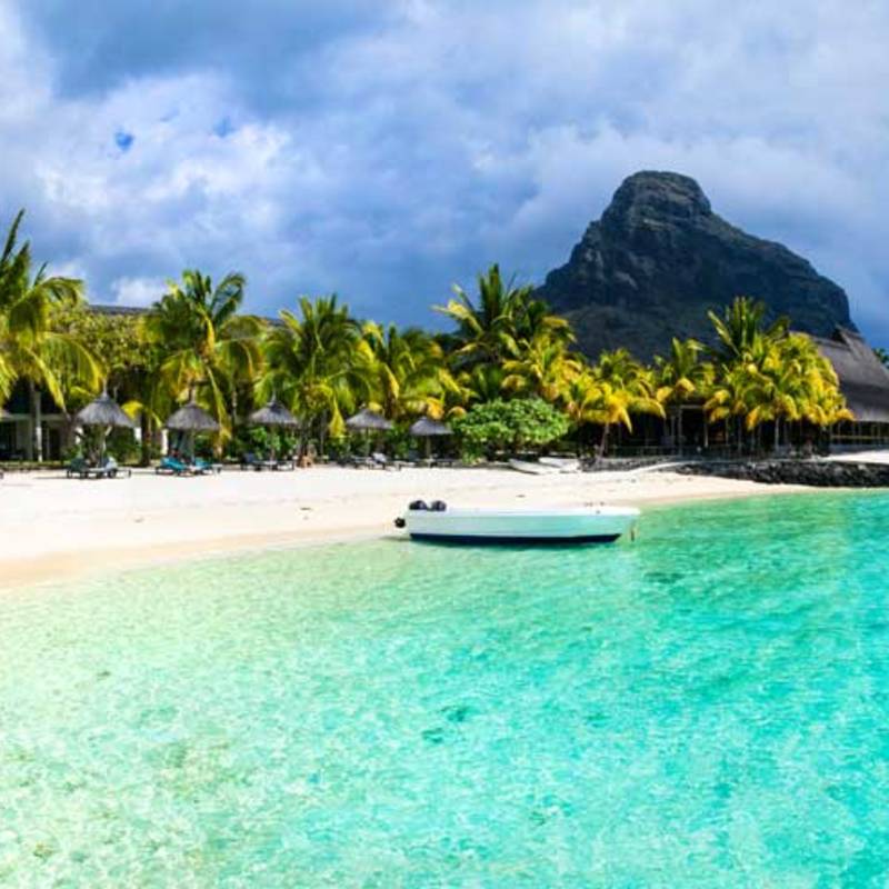 Weißer Sandstrand und Boot mit Berg im Hintergrund