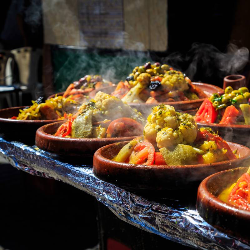 Blick von vorne auf dampfende Gemüse Tajines auf einem Markt in Marokko