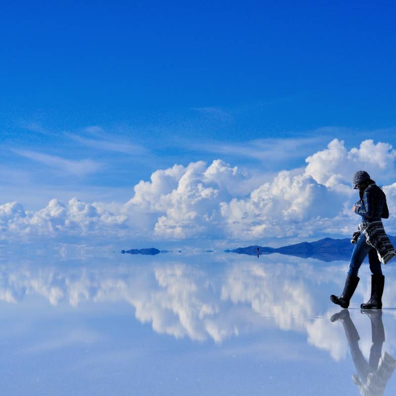 Girl on surface of salt lake Salar de Uyuni in Bolivia with sky reflection, South America