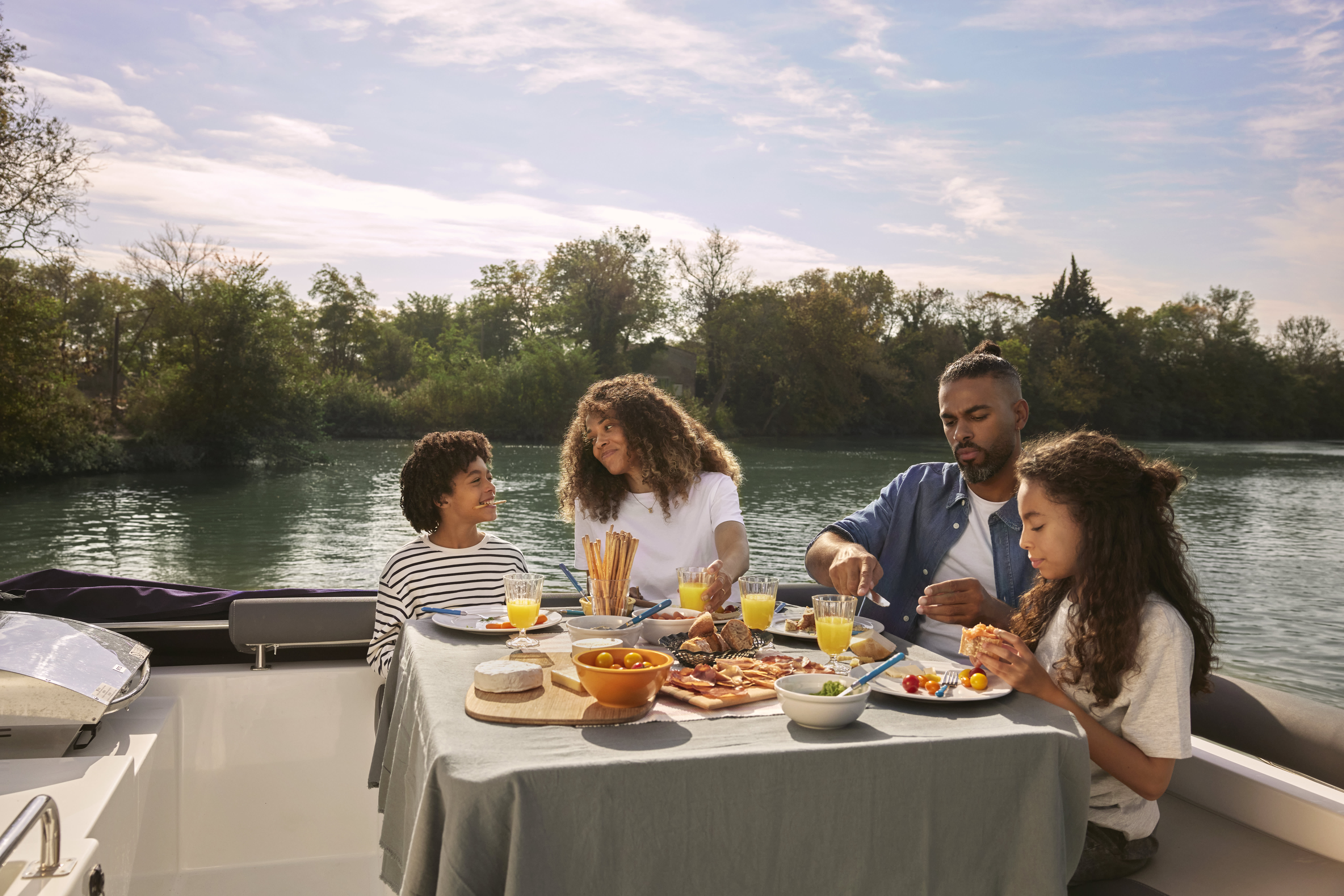 Vierköpfige Familie am Mittagstisch auf dem Oberdeck eines Horizon-Bootes.