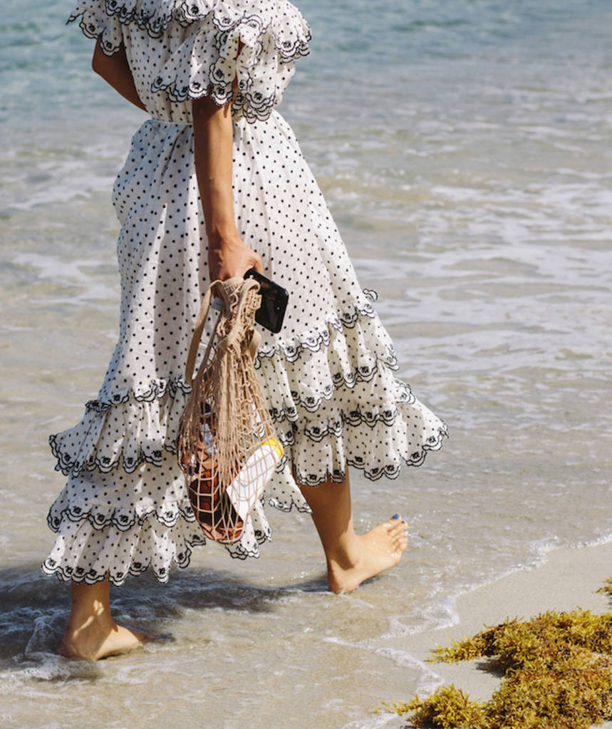 Woman walking on beach carrying fisherman bag