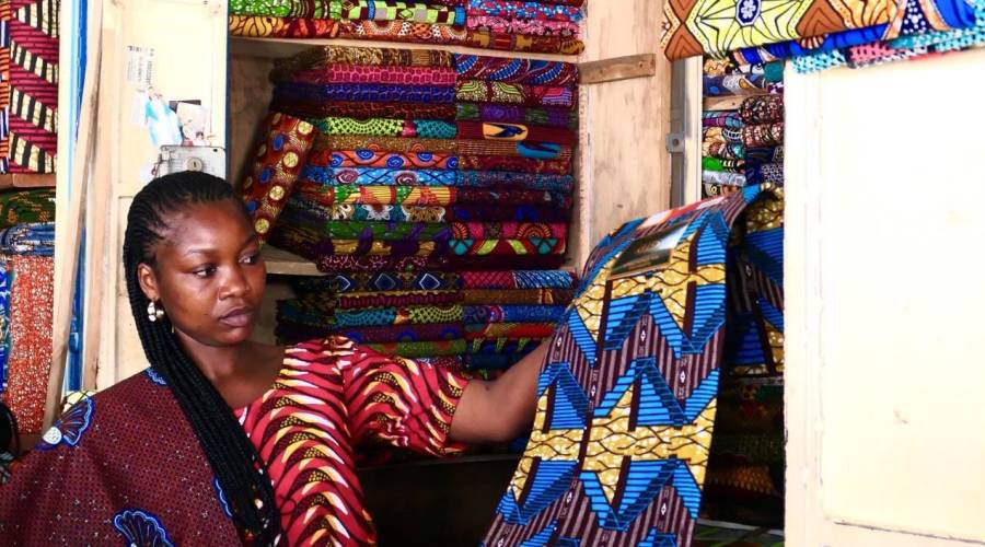 Nana Benz holds up a wax cloth in the Lomé Market