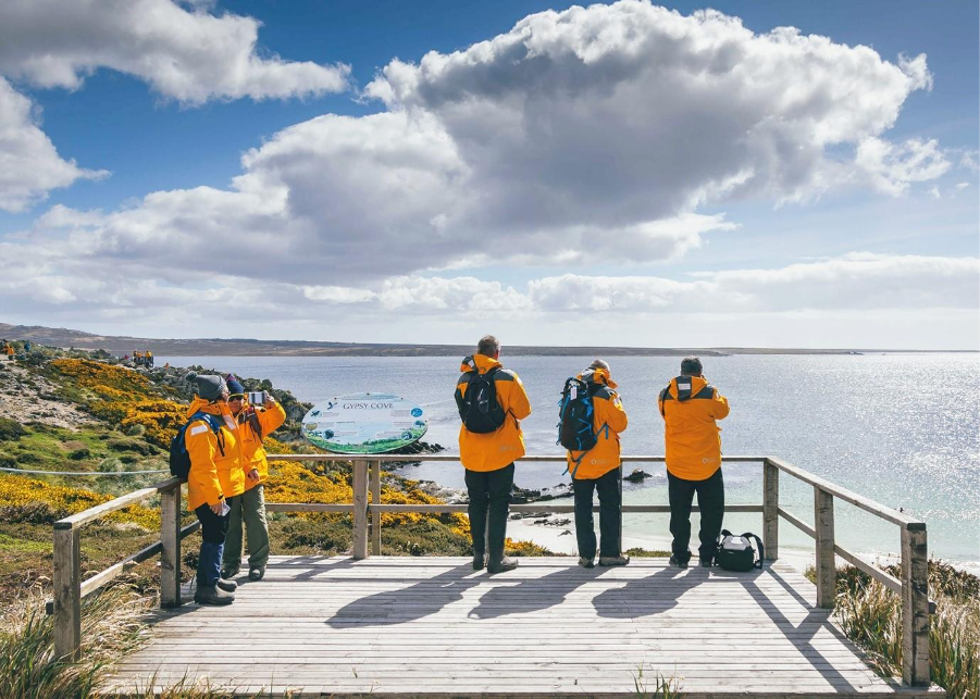 Guests on an observation deck viewing ocean & clear sky 