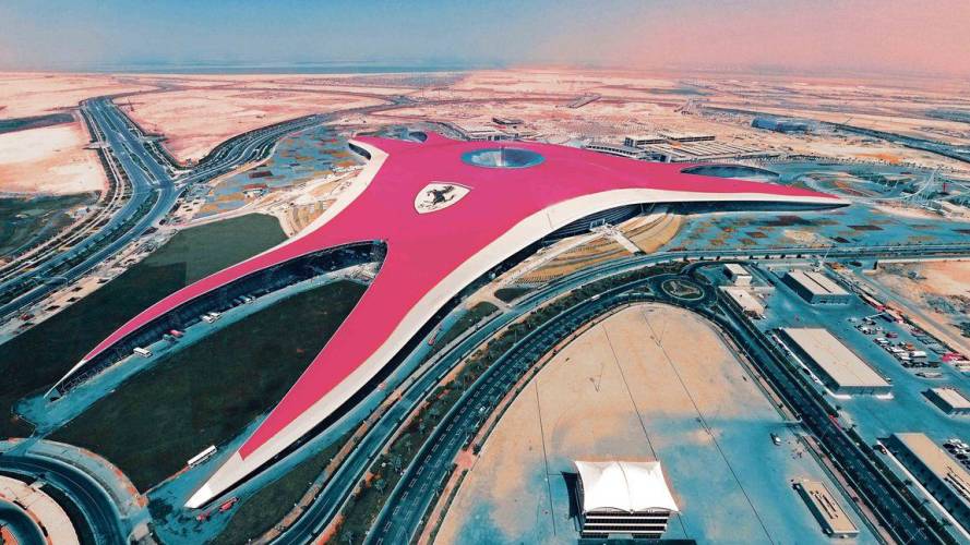 a train is parked on the beach with Ferrari World Abu Dhabi in the background