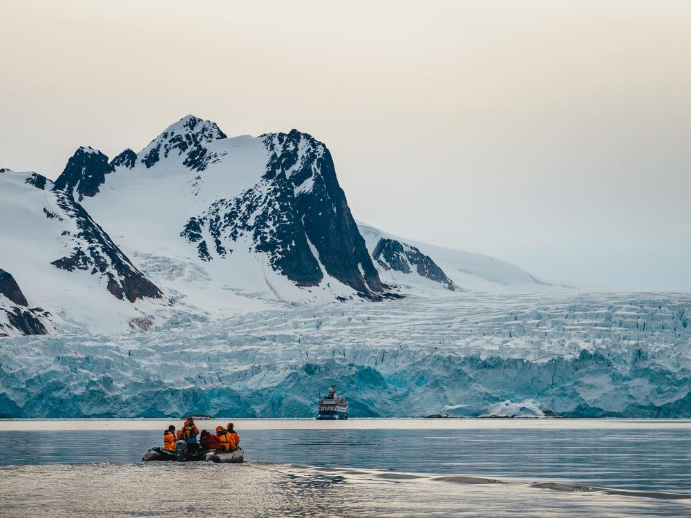 A Zodiac beneath glaciers and mountains in Svalbard